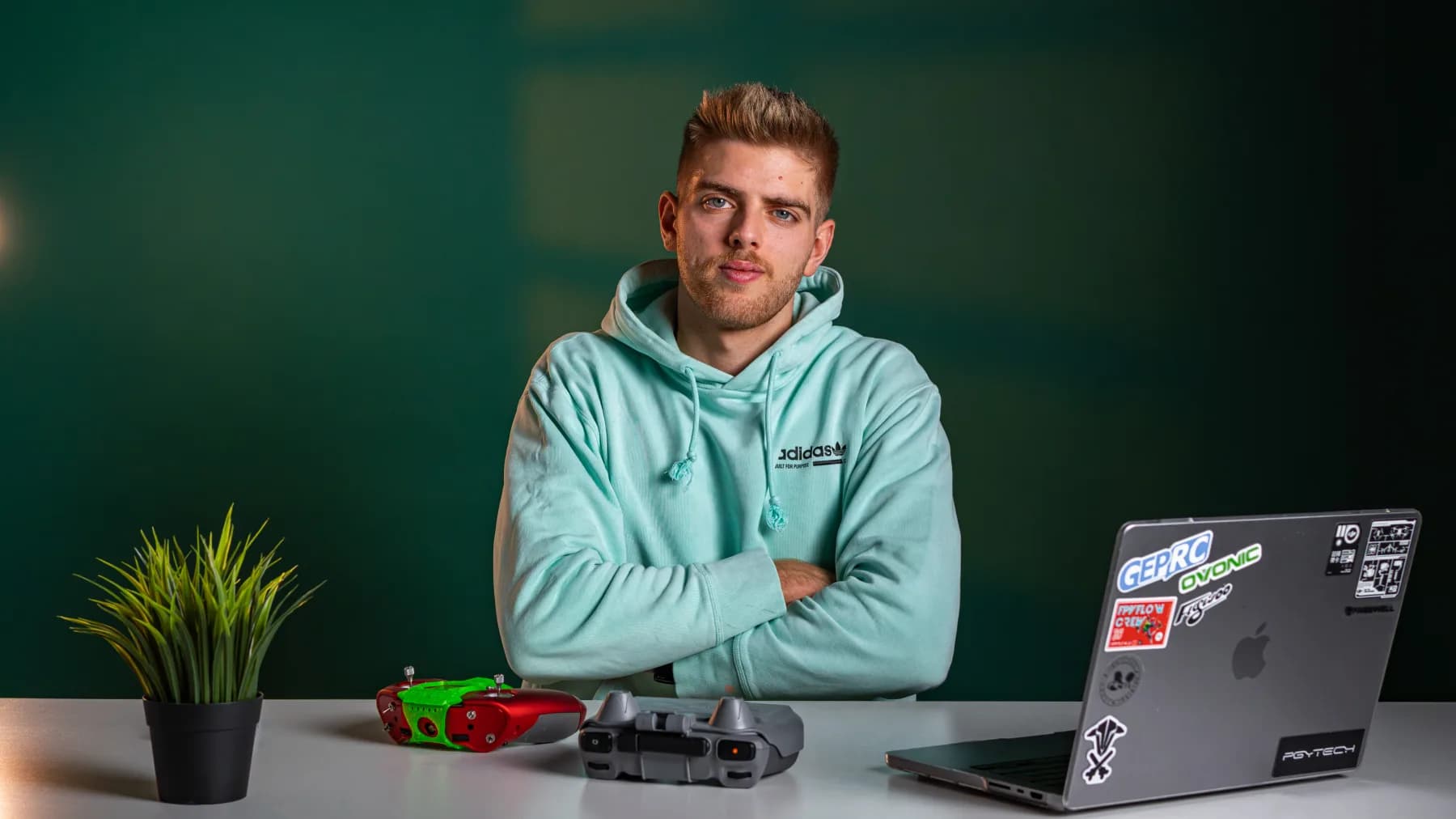Elia Zanetta at his desk with FPV goggles, a drone controller and a sticker-covered laptop.