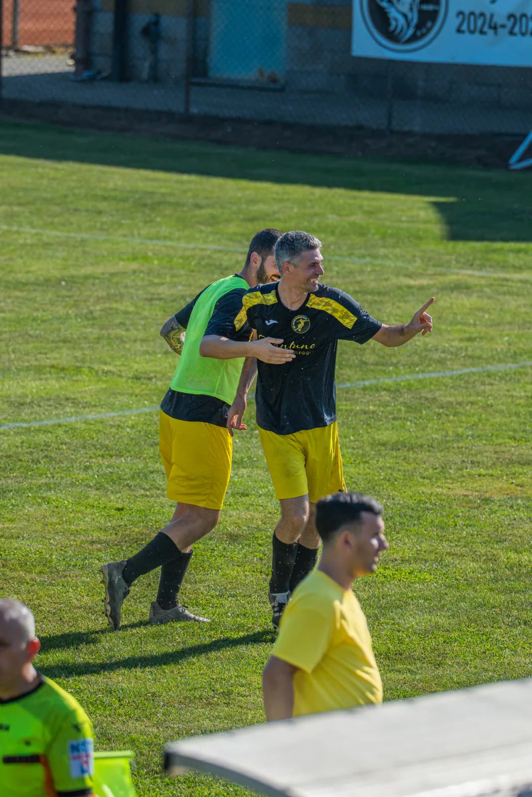 Footballers celebrating a goal at the edge of the pitch.