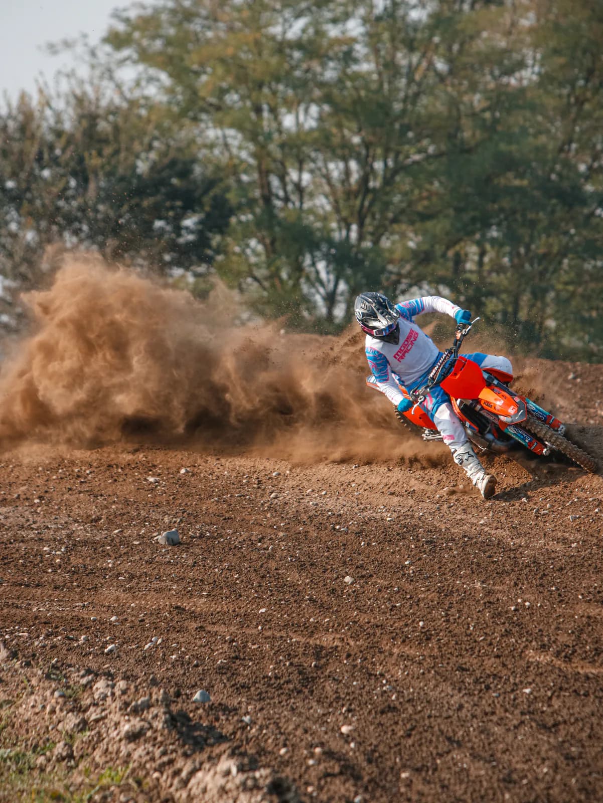 KTM rider tearing a cloud of dust out of a corner.